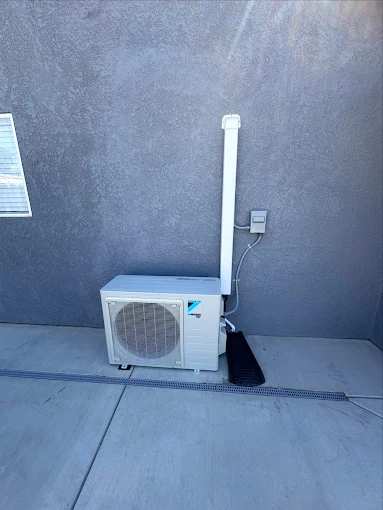 Outdoor heat pump unit installed on concrete pad with professional refrigerant line connections